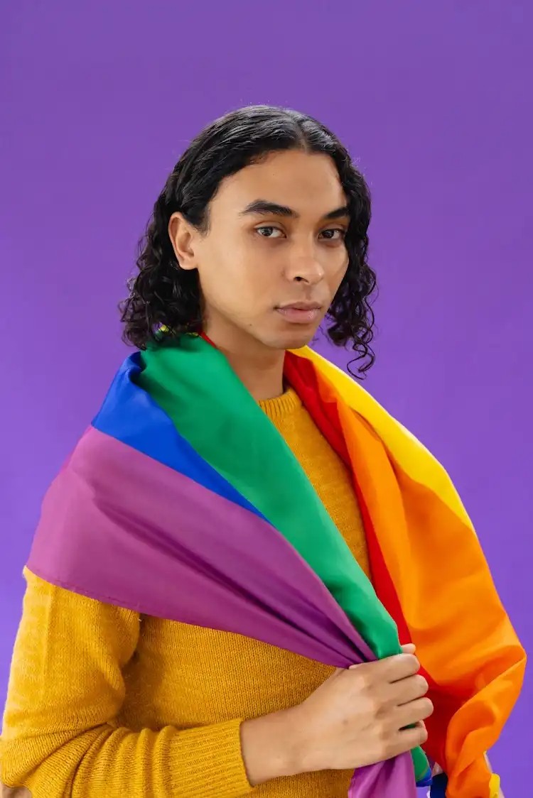 A smiling person holding a rainbow flag