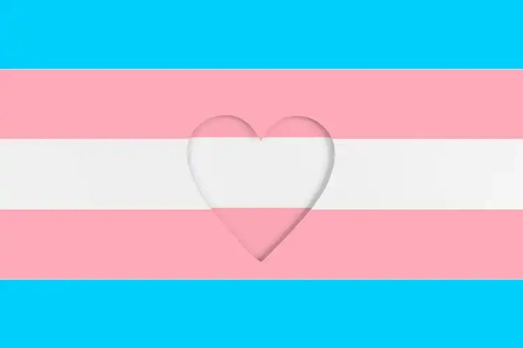 Hands holding a heart over a transgender flag