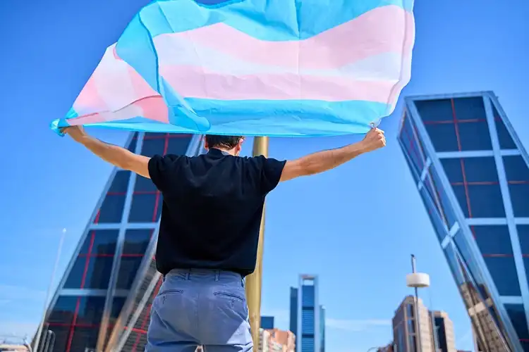 A transgender pride flag displayed in an urban setting.