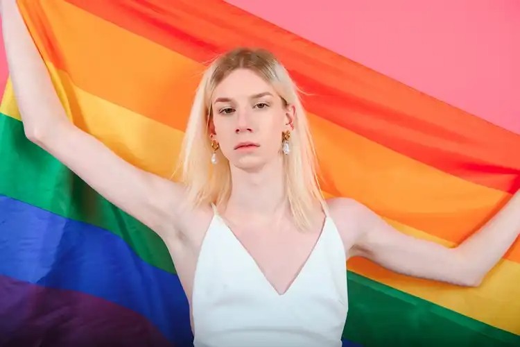 Smiling person holding a pride flag outdoors